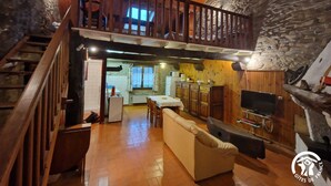 A rustic interior with a wooden staircase, a loft bedroom, a dining area, and a kitchen. - Gîte 42 - LACAUNE - Gîte (LACAUNE)