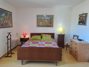 A bedroom with a bed, a nightstand, a dresser, a lamp, and two wall hangings. - Crameaux - SAINT-ANDRE (SAINT-ANDRE)