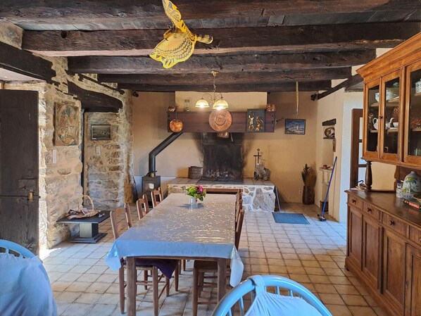 Ein rustikaler Essbereich mit Steinwand, Holzbalken, Kamin und einer Holzvitrine mit Glastüren.