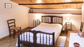 Une chambre à coucher avec un lit en bois, une chaise, des tables de chevet et une lampe.