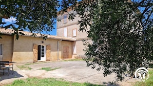 A rustic building with a tiled roof, wooden shutters, and a small outdoor seating area. - Le Chinchilla - GAILLAC (GAILLAC)