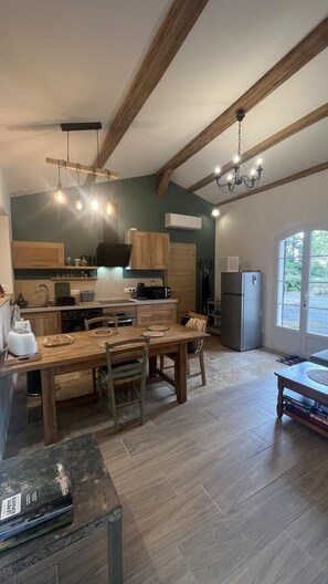 A kitchen with wooden beams, a dining table, chairs, a refrigerator, and a window with a view.