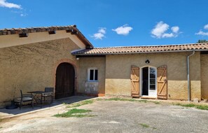 A rustic building with a tiled roof, a large wooden door, and a small window.