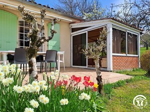 Una casa con patio, un tavolo da pranzo e diverse fioriture.