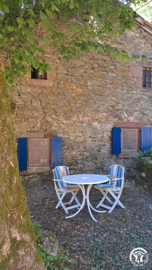 A stone building with a rustic charm, featuring a small table and two chairs in front. - Cambert - MURAT-SUR-VEBRE (MURAT-SUR-VEBRE)