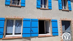 A building with multiple windows, some with blue shutters and balconies.
