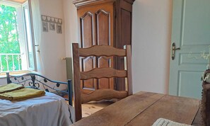 Ein Schlafzimmer mit einem hölzernen Bett, einem Holztisch und einem Fenster mit Blick auf Grünflächen.
