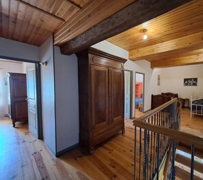 Ruime kamer met houten vloeren, een grote kledingkast, een trap met metalen leuning en een bed met wit frame.