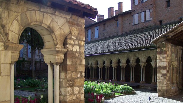 Une cour intérieure agrémentée d’arches en pierre et d’un chemin pavé.