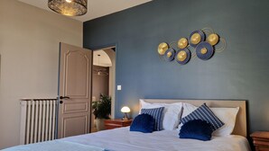 A bedroom with a bed, bedside tables, a wall-mounted decorative piece, and a radiator.
