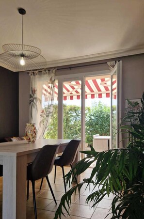 A modern dining area with a large table, chairs, and a hanging light fixture.