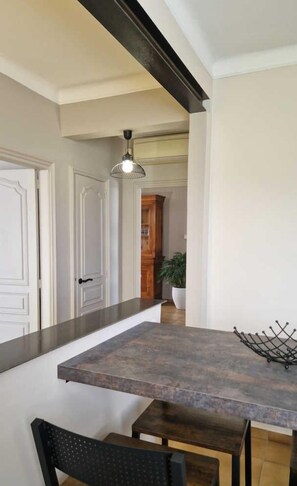 A kitchen with a large island, two bar stools, a hanging light fixture, and a potted plant.