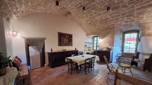 A rustic dining area with a stone ceiling, a table with chairs, and a kitchen in the background. - The kitchens of Château d'Appelle (APPELLE)