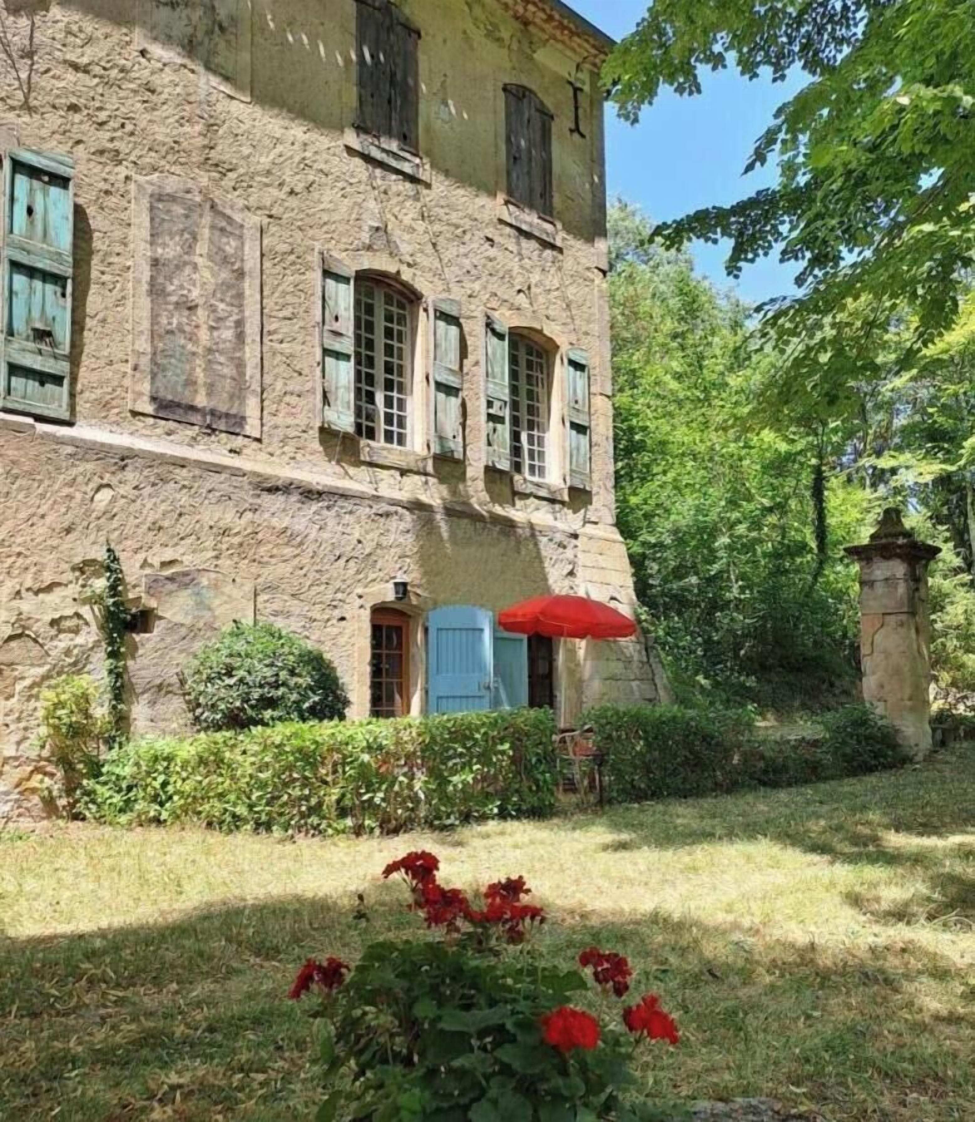 Un edificio in pietra con diverse finestre e un ombrello rosso.