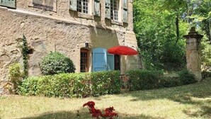 A stone building with multiple windows and a red umbrella. - The kitchens of Château d'Appelle (APPELLE)