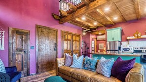 A cozy living room with a leather sofa, teal ottoman, and wooden doors. - Stay in the Tree House! One of a Kind Experience! (Branson)