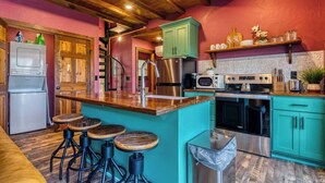 A kitchen with a central island, bar stools, a refrigerator, a stove, and a sink. - Stay in the Tree House! One of a Kind Experience! (Branson)