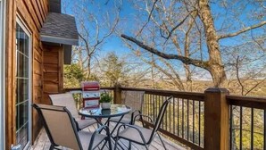 A wooden deck with a table and chairs, a barbecue grill, and a view of trees and sky. - Stay in the Tree House! One of a Kind Experience! (Branson)