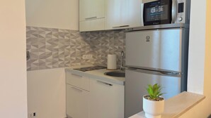 Eine kleine Küche mit Kühlschrank, Mikrowelle und Spüle.