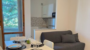 Ein Essbereich mit einem für zwei gedeckten Tisch, einem grauen Sofa und einer Küche im Hintergrund.