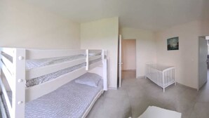A room with bunk beds, a crib, and a door leading to another room. - Les Acacias d'En Cassé (LAVAUR)