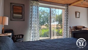A bedroom with a large bed, a desk, a chair, and a piano. - Au pré vert - SAINT PIERRE DE TRIVISY (SAINT PIERRE DE TRIVISY)