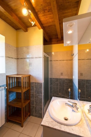 A bathroom with a wooden shelf, a sink, and a mirror.