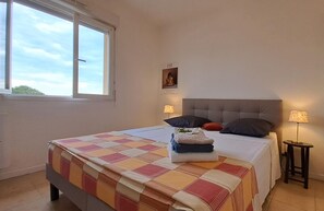 Ett sovrum med en stor säng, två sänglampor, ett fönster och en dörr.