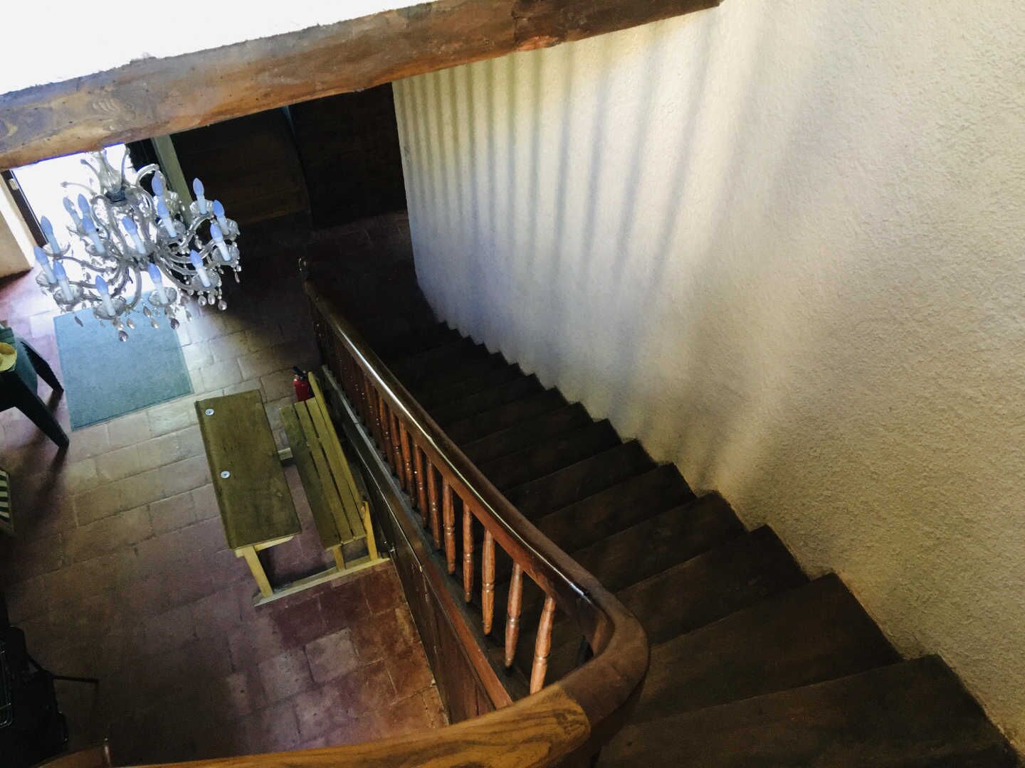 Un escalier en bois avec une rampe, un lustre et une porte en bas.