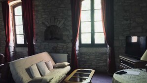 A cozy living room with a stone wall, a sofa, a coffee table, and a television.