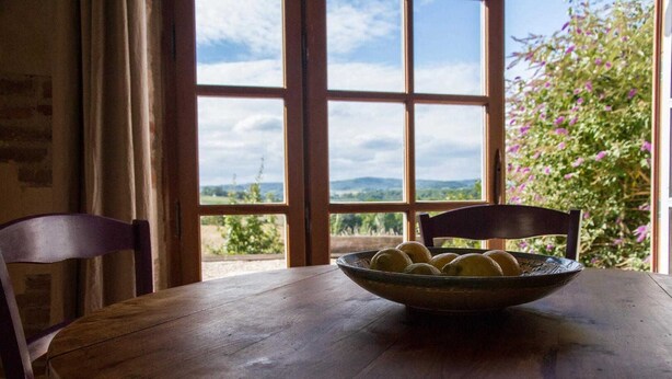 A wooden table with a bowl of lemons and a chair. - The Yellow Crocodiles (CASTELNAU DE MONTMIRAL)