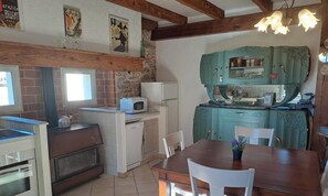A kitchen with a brick wall, a white refrigerator, a microwave, and a teal cabinet.