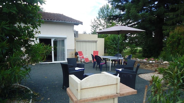 An outdoor patio area with a table and chairs, a stone bench, and a covered seating area. - Enjalbert - Albi - Gîte (Albi)