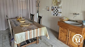 A dining area with a table set for two, a wooden cabinet with a sink, and a wall with a map. - Enjalbert - Albi - Gîte (Albi)