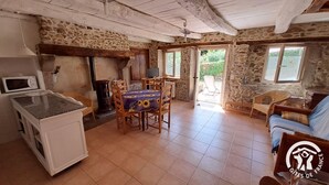 Une cuisine rustique avec un mur en pierre, des meubles en bois et un sol carrelé.