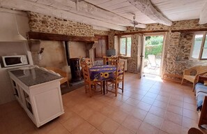 Une cuisine rustique avec un mur en pierre, des meubles en bois et un sol carrelé.