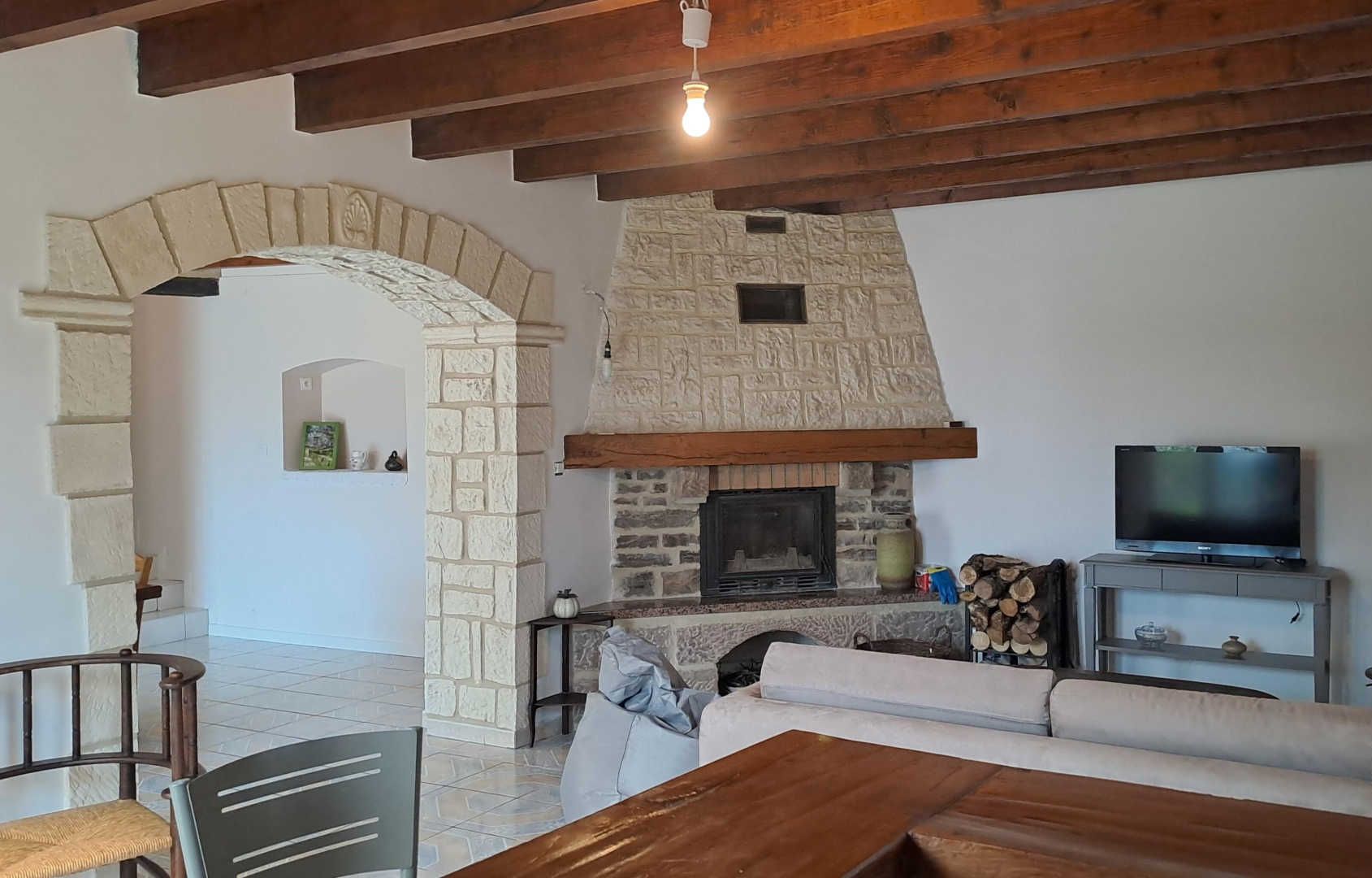 Una sala de estar con chimenea de piedra, televisor y sofá.