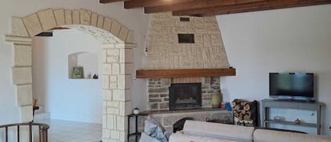 Una sala de estar con chimenea de piedra, televisor y sofá.