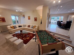 Uma sala de estar com mesa de futebol, sofá e mesa de centro.