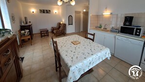A compact living space with a dining area, kitchen, and a small seating area. - La Rivaillée - PARISOT (PARISOT)
