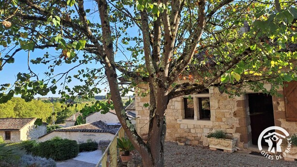 A stone building with a tiled roof, a tree in front, and a clear sky. - La Vigneronne - CESTAYROLS (CESTAYROLS)