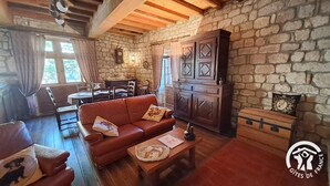 A cozy living room with a stone wall, wooden furniture, and a fireplace. - La Vigneronne - CESTAYROLS (CESTAYROLS)