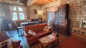 A cozy living room with a stone wall, wooden furniture, and a fireplace.