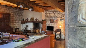 A rustic interior with a stone fireplace, wooden beams, and a cozy seating area.