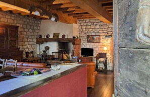 Un intérieur rustique avec une cheminée en pierre, des poutres en bois et un coin salon confortable.