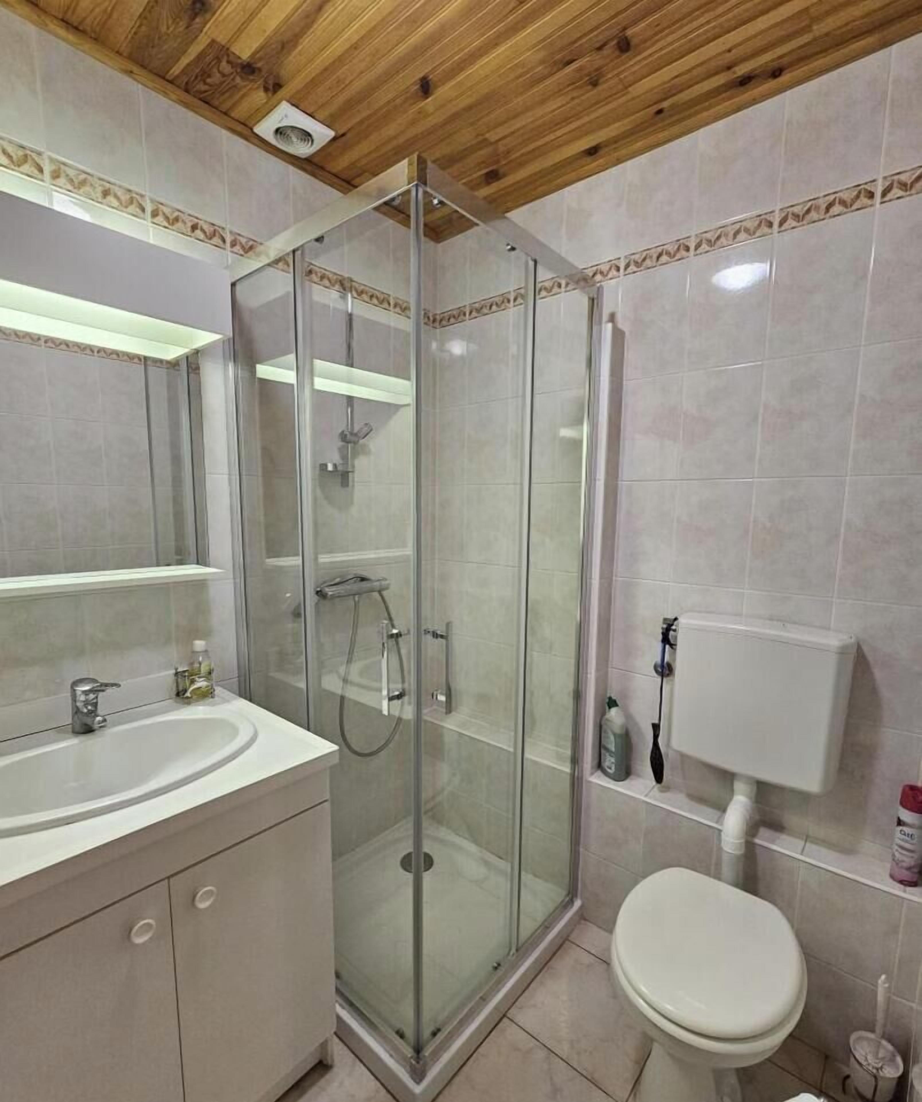 A bathroom with a glass-enclosed shower, a sink, and a toilet.