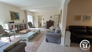 A living room with a sofa, armchair, and a coffee table. There is a bookshelf and a cabinet in the background. - Le relais de la poste (CASTELNAU DE MONTMIRAL)