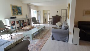 A living room with a sofa, armchair, and a coffee table. There is a bookshelf and a cabinet in the background. - Le relais de la poste (CASTELNAU DE MONTMIRAL)