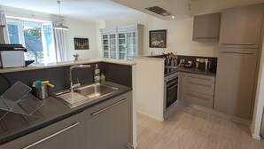 A modern kitchen with a central island, stainless steel appliances, and a view of the outdoors. - Le relais de la poste (CASTELNAU DE MONTMIRAL)