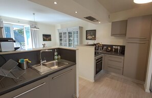 A modern kitchen with a central island, stainless steel appliances, and a view of the outdoors. - Le relais de la poste (CASTELNAU DE MONTMIRAL)